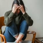 dziewczyna ukrywa twarz w dłoniach, prawdopodobnie się boi